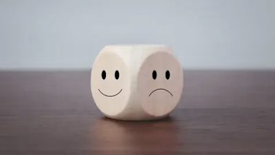 Smiling and sad symbols on wooden blocks on a gray background.